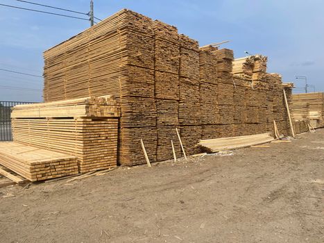 Wooden boards, lumber, industrial wood, timber. Pine wood timber stack of natural rough wooden boards on building site. Industrial timber building materials.