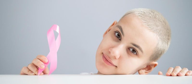 Young woman with pink ribbon on a white background. Mammary cancer.