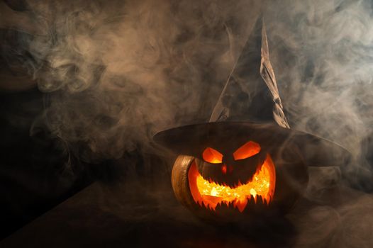 A creepy pumpkin with a carved grimace in the smoke. Jack o lantern in the dark