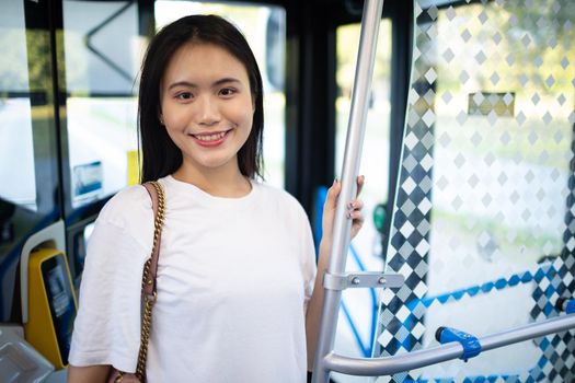 Asian Woman take a ride stand in public transport bus or tram