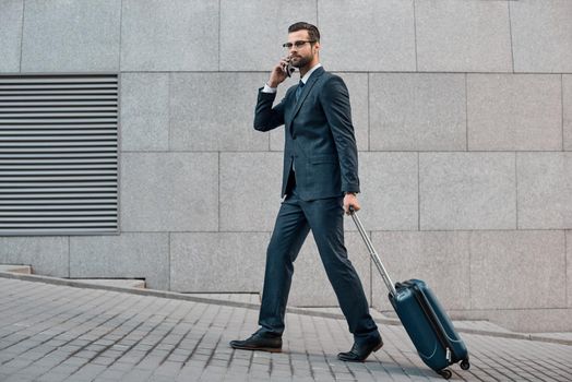 Full length of young man in full suit gesturing and shouting while walking outdoors