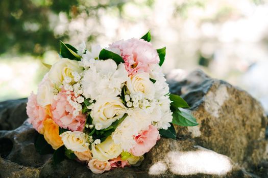 Wedding bouquet of fresh beautiful flowers. The bride's bouquet lies on a stone.