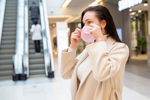 a woman puts on a medical protective mask in a public place