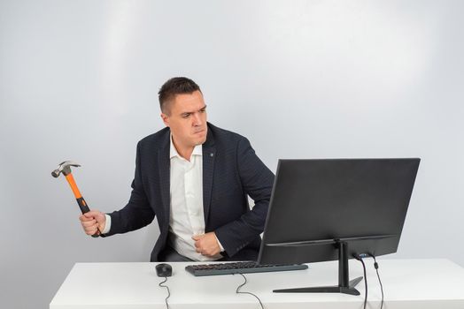 The man gets angry and smashes the monitor with a hammer. An office worker in a rage breaks the computer