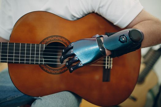 Young disabled man with artificial prosthetic hand plays on guitar strings at shop