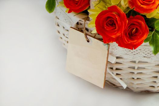 close-up greeting card on a white basket with scarlet roses and yellow chrysanthemums. white background for cutting. card blank for the inscription copy space. mock up