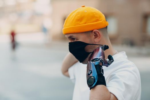 Young disabled man put on medical protective face mask with artificial prosthetic hand