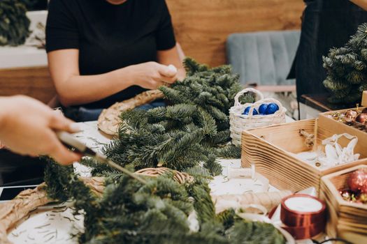 Woman making christmas wreath. Concept of florist's work before christmas holidays. Creating a Christmas wreath of spruce branches and a cardboard frame. Decoration for the house for Christmas.