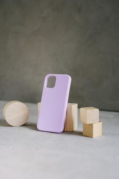 Purple silic case for smartphone and wooden figures. Vertical image.