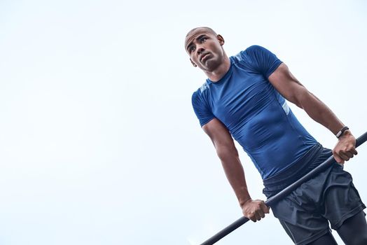 An african man is exercising at open air gym. Close-up photo of black african handsome guy in sports clothes is doing exercises for his hands