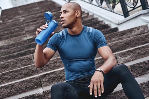 Young male jogger athlete training and doing workout outdoors in city.