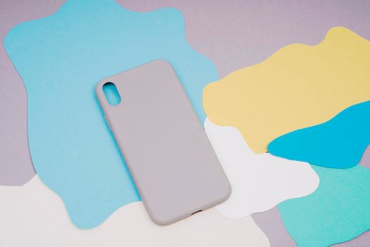 The gray silicone case for the smartphone lies on a multi-colored background. Protect your phone.