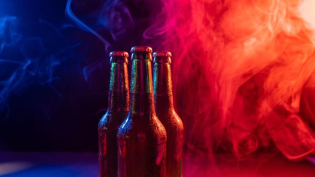 Three bottles of beer in a blue-pink mist