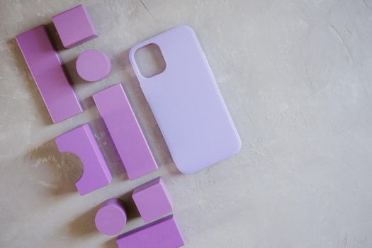 Abstract figures made of natural wood painted purple. Silicone protective case for smartphone on a gray textured background.