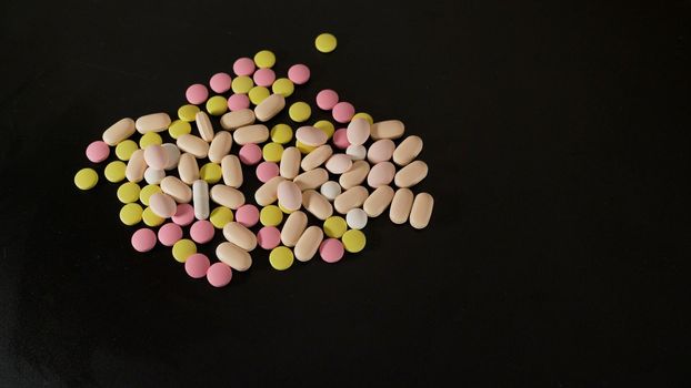 Tablets of different sizes close-up. Medicines tablets, capsules, pills of different kinds, sizes and colors, piled up in bulk.Colored vitamin close up.