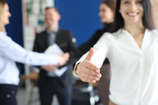 Beautiful smiling business woman stretches out her hand in the office. Greeting partners to business at a meeting, cooperation