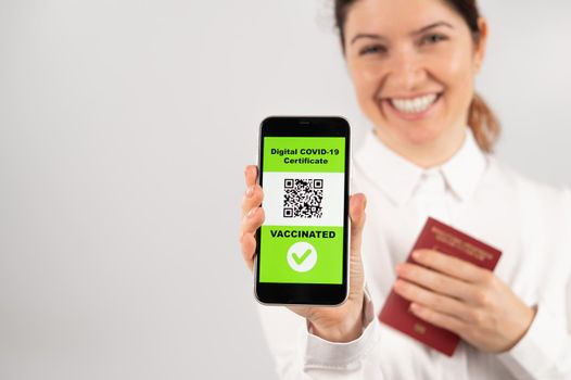 Woman holding passport and phone with qr code about vaccination