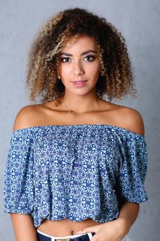 Beautiful black woman portrait. Worth a gray background and smiling beauty fashion style curly hair with white strands view of the eye in the camera