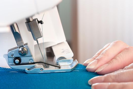 Women's hands at work on sewing machine. Overlock sewing.