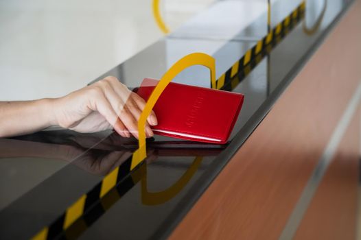 An airport employee at the check-in counter takes the passenger's passport