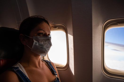 Caucasian woman wearing a medical mask on board the plane