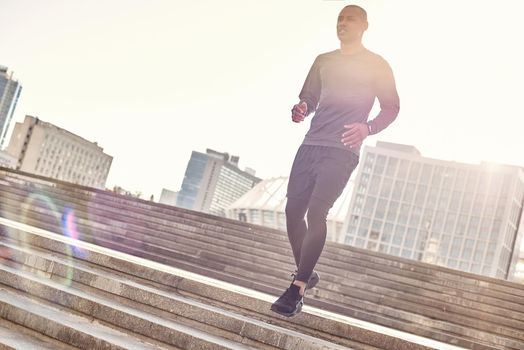 Healthy way of life. Full length portrait of athletic african man in sportswear running down stairs on a sunny warm day. Urban environment. Cardio training. Morning workout. Sport motivation concept. Fitness concept