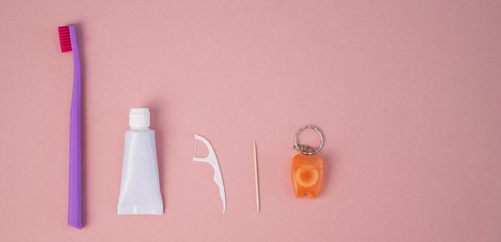 Oral hygiene products on a pink background. Toothbrush toothpaste dental floss and toothpick. Copy space