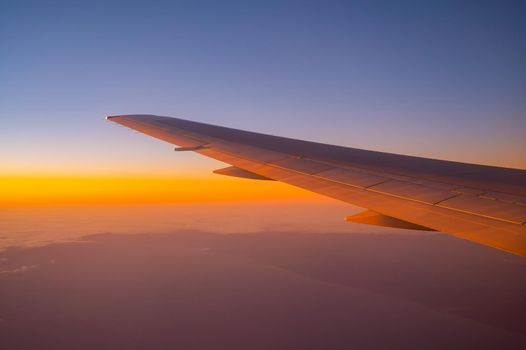 View of the wing of an airplane during flight from the window at sunset