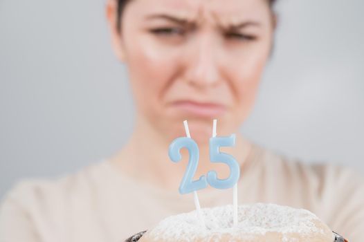 The unhappy woman is holding a cake with candles for her 25th birthday. The girl is crying on her anniversary. Copy space.