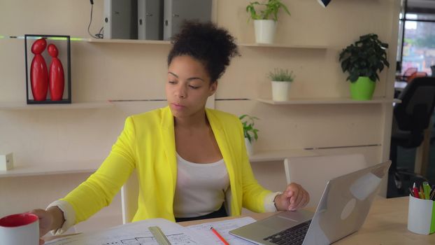 Young professional lady working with computer drinking tea.