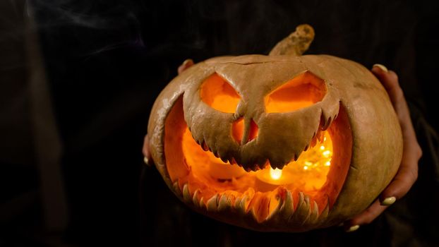 The witch is holding a pumpkin jack about a lantern glowing in the dark. Halloween