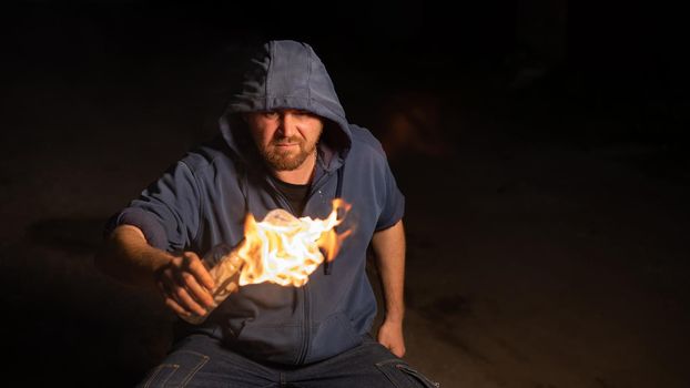 The man in the hood is holding a burning bottle. Molotov cocktail