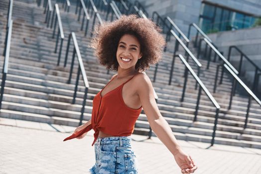 Young woman free style on the street walking near concrete stairs spinning looking camera laughing cheerful