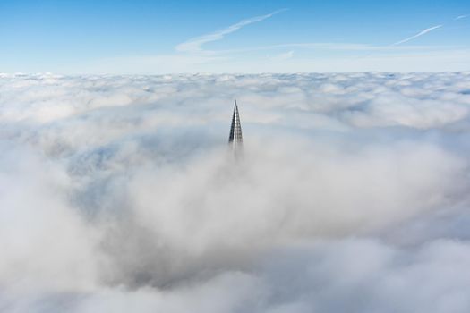 Russia, St. Petersburg, 14 October 2021: The top of the tallest skyscraper in Europe above the clouds, the building of the Gazprom oil company, the spire of a metal and glass structure. High quality photo