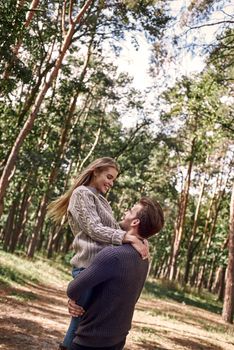Outdoor happy couple in love posing in autumn forest. Young woman and man having fun outdoor