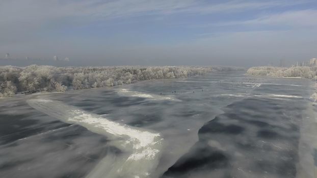 The frozen river in the forest in winter, the snow on the trees, the view from the air 4k video