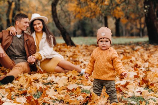 Father and mother with son walking in the autumn Park. A family walks in the Golden autumn in a nature Park