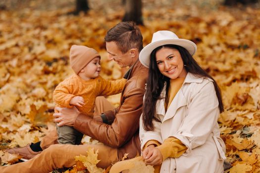 Father and mother with son walking in the autumn Park. A family walks in the Golden autumn in a nature Park