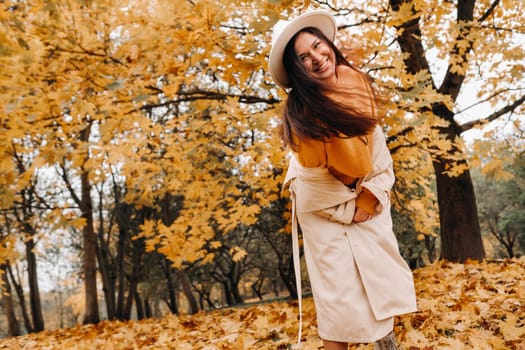 a cheerful girl in a white coat and hat smiles in an autumn Park.portrait of a smiling woman in Golden autumn