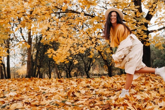 a cheerful girl in a white coat and hat smiles in an autumn Park.portrait of a smiling woman in Golden autumn