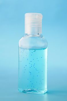 transparent hand sanitizer liquid in a container on blue backgorund .