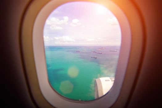 beautiful view from the window of the plane to the sea and ships in the sun. carefree view from porthole landing airplane