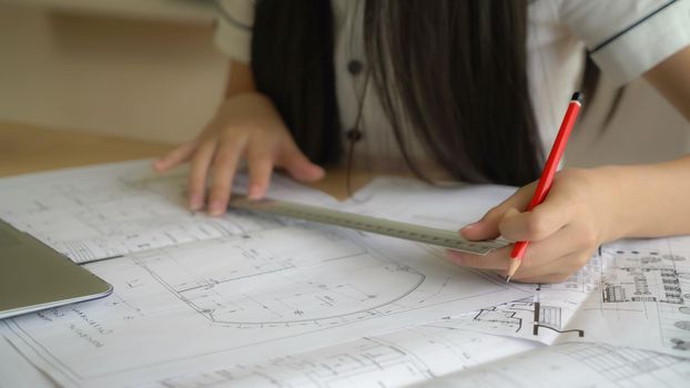 Closeup woman architect working with architectural plan. On working place laptop