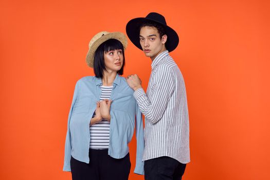 man and woman in hats posing fashion orange background. High quality photo