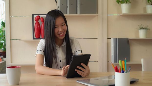 Asian business lady using touch screen tablet talking with friend or client use application. wearing in casual formal white shirt