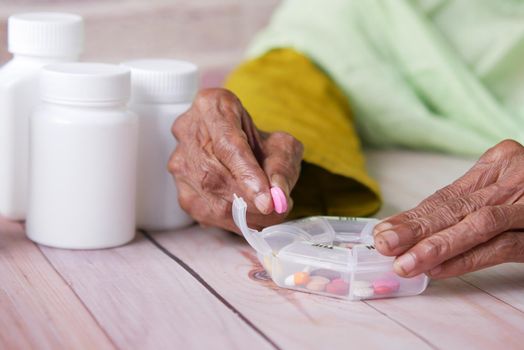 senior women hands taking medicine from a pill box .