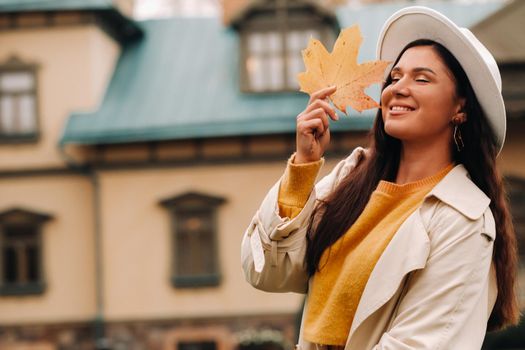 a girl in a white coat and hat smiles in an autumn Park.Portrait of a woman in Golden autumn