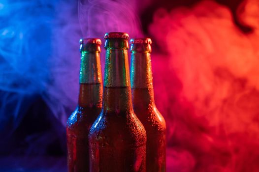 Three bottles of beer in a blue-pink mist