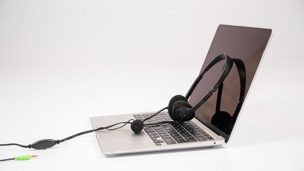 Headset on laptop keyboard on white background