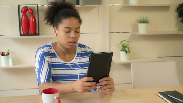 Portrait mixed race woman has video call using application on touch screen tablet. Mulatto lady smile and emotionally speaking.